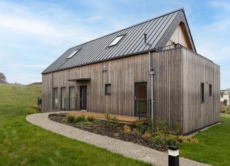 A 2-storey wooden eco lodge surrounded by an open field.