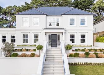 An elevated, contemporary house approached by a line of steps overlooks an ornamental garden.