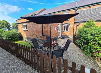 A brick-built Shropshire barn conversion overlooks a shrub-filled courtyard with a picket fence.