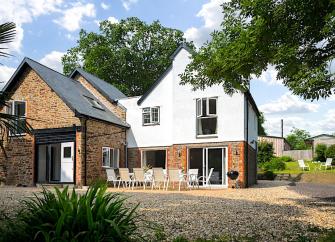 A twin-gabled holiday cottage nestles between two tall trees.