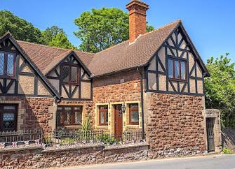 Exterior of a stone-built holiday cottage in Dunster with a secure front garden.