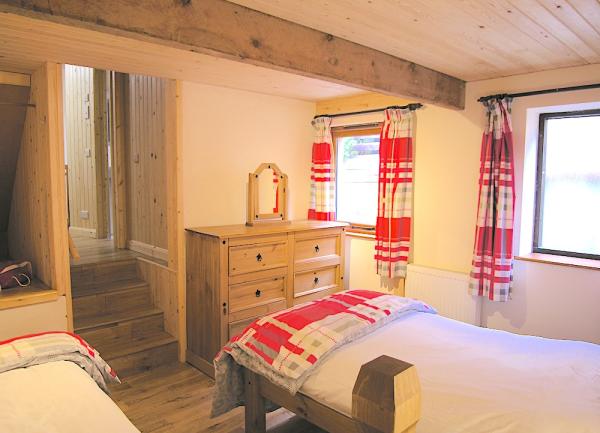 A twin bedroom with beds, chest of drawers and a mirror.