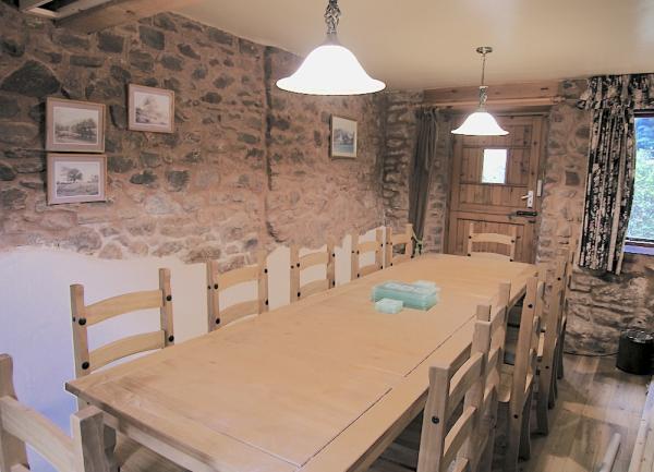 Dining room with exposed stone walls and wooden table and chairs seating 12 guests.