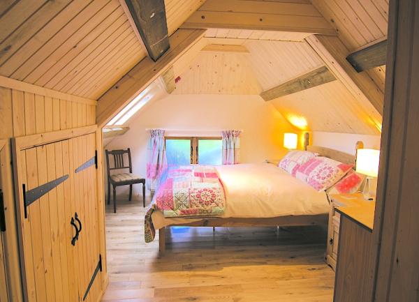 Oak beamed double bedroom with bed, fitted wardrobe, chest of drawers and bedside chair.