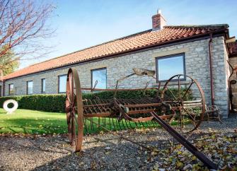 A large, single storey barn conversion overlooks a lawn.