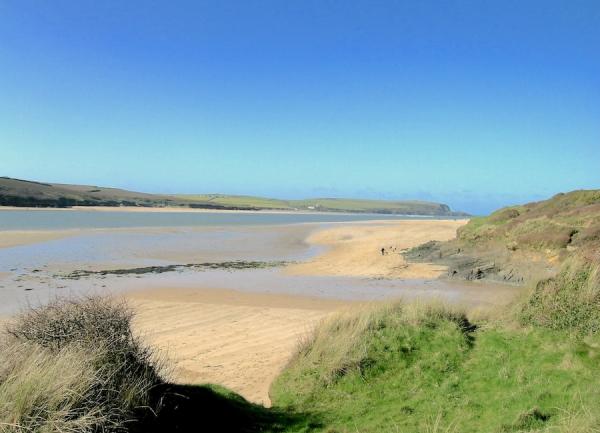 Large sandy Cornish beach backed by dunes at low tide.