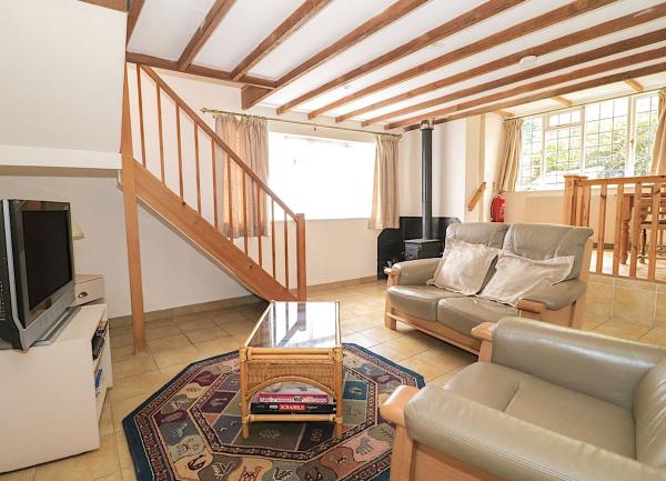 An Oak-beamed Exmoor cottage lounge with a comfy sofa, armchair and coffee table.
