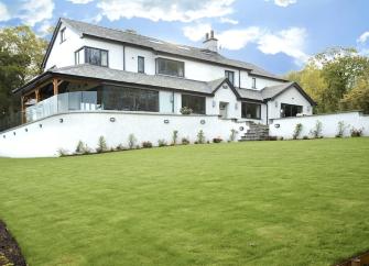 Large Windermere holiday cottage on a terrace overlooking a spacious lawn.