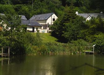 A barn conversion overlooks a calm lake.