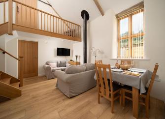 An open plan lounge with sofas, TV and a dining table and chairs.