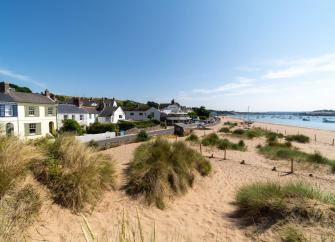 A row of beach cottages overlook dunes and a sandy beach at low tide