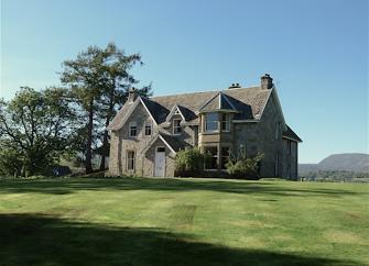 A large detached, Victorian Gothic house surrounded by spacious lawns.