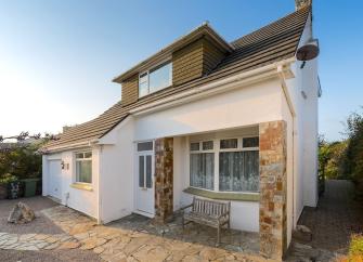 Exterior of a large, modern, brick-built chalet bungalow overlooking a paved patio