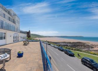 Seating on a beach apartments terrace overlooks a large sandy beach at low tide