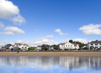 3 cottages overlook a sandy beach at low tide.