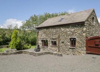 A garden table with a parasol sits outside a stone-built barn conversion in Cumbria.