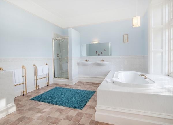 Spacious bathroom with a bath, twin basins, shower and towel rails.