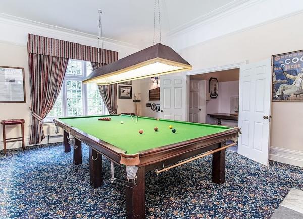 A snooker room with a full-size table with an overhead light.