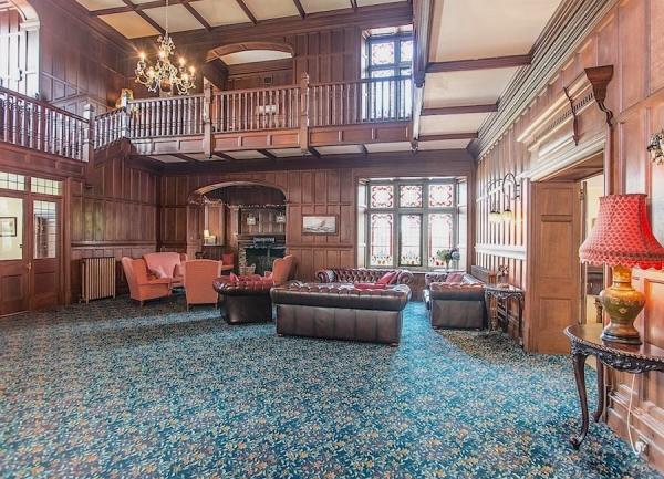 A wide, galleried entrance hall with sofas and armchairs.