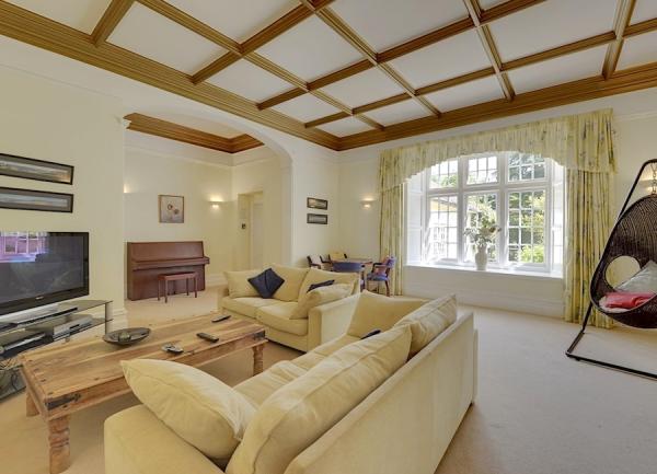 A lounge with sofas, coffee table, widescreen TV. and a piano.