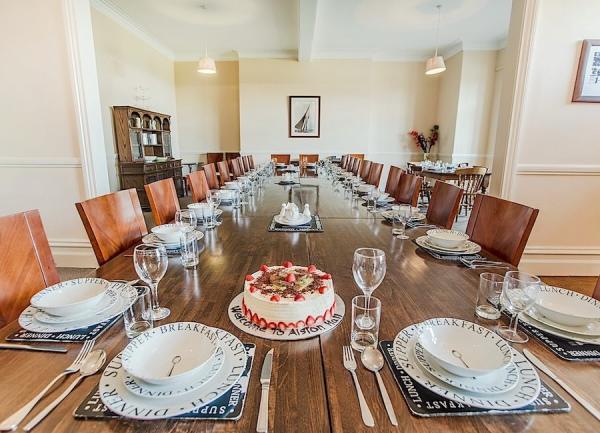 A long wooden dining table with 20 place settings laid for dinner.