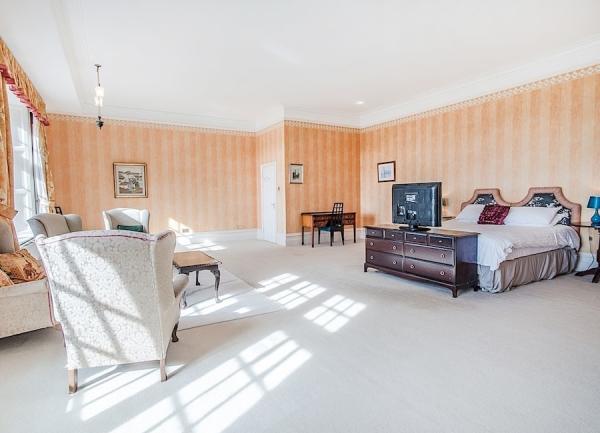 Spaciopus double bedroom with bed, dressing table, armchairs and TV.
