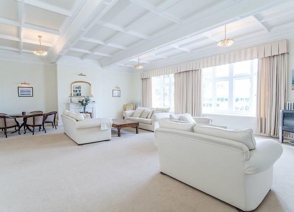 half of a large double bedroom with 3-sofas, TV and a card table with chairs.