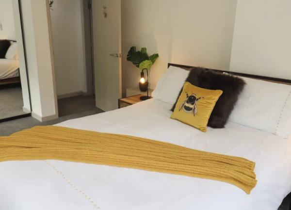 A bedroom with a double bed,, twin bedside cabinets with tablke lights and a mirror-fronted fitted wardrobe.