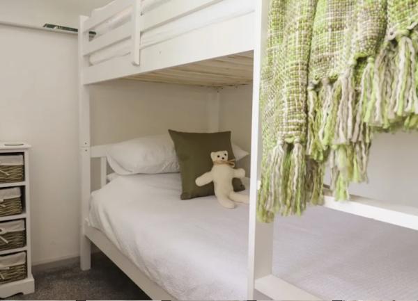 Bedroom with bunk beds, and a bedside cabinet with 4 storage  baskets.