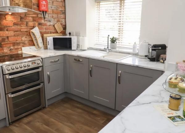Fitted floor units on 3 sides with an integrated oven and a microwave and toaster and microwave on worktops.