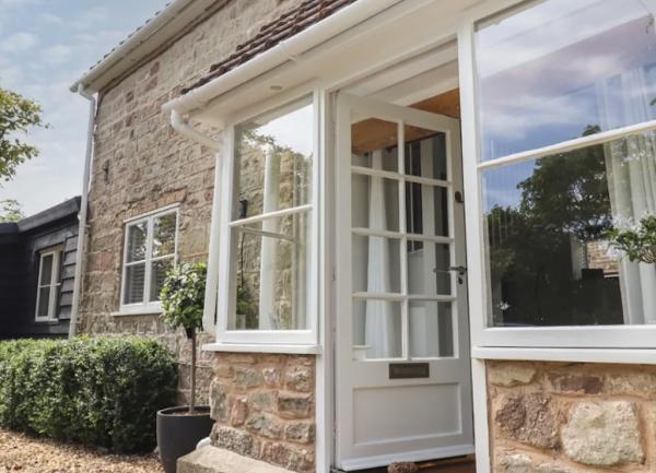 Exterior to the entrance porch with a front door with glass pains flanked by large windows.