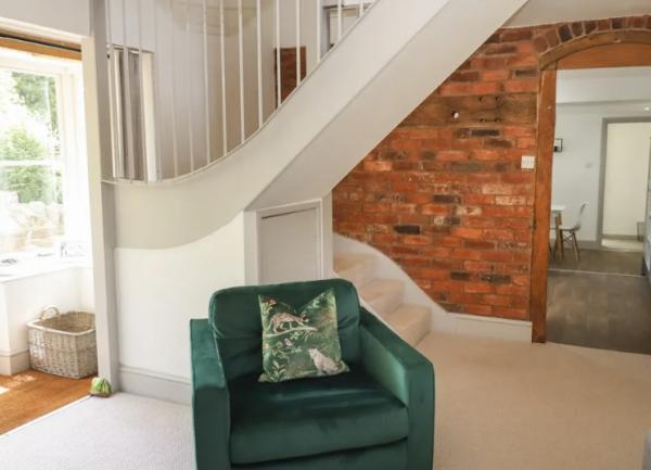 A lounge corner with a door to the garden, 2 cosy chairs and stairs at the rear.