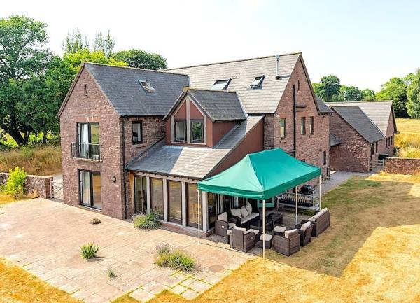 Exterior of a large, twin-gabled brick farmhouse with a gazebo.