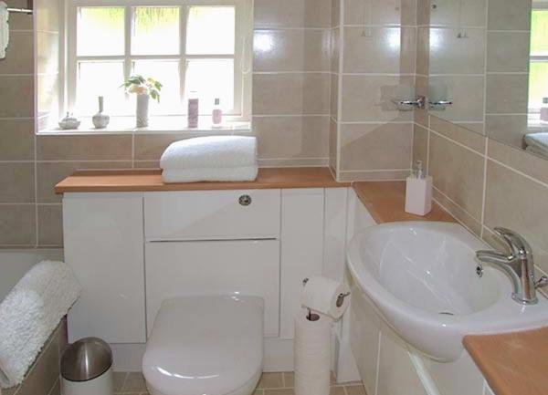 A bathroom with a bath and fitted cupboards incorporating an integrated washbasin and WC.