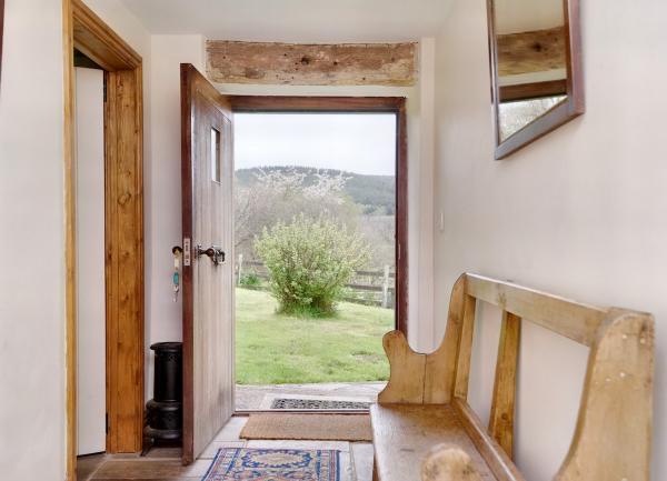 A cottage hallway with an open front door offering garden and far-reaching rural views.