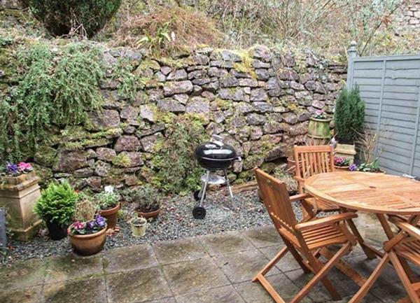 A paved courtyard BBQ patio with an outdoor table and chairs. 