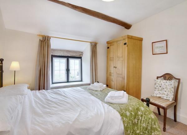 A bedroom with a double bed, bedside chair and a wardrobe.