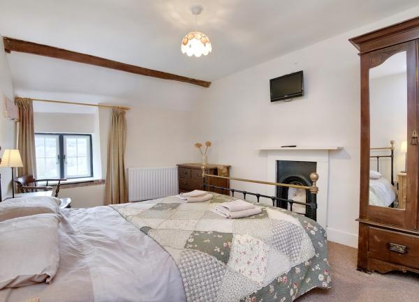 Double bedroom with a bed, wall-mounted TV above an antique fireplace and a fitted wardrobe with mirrors.
