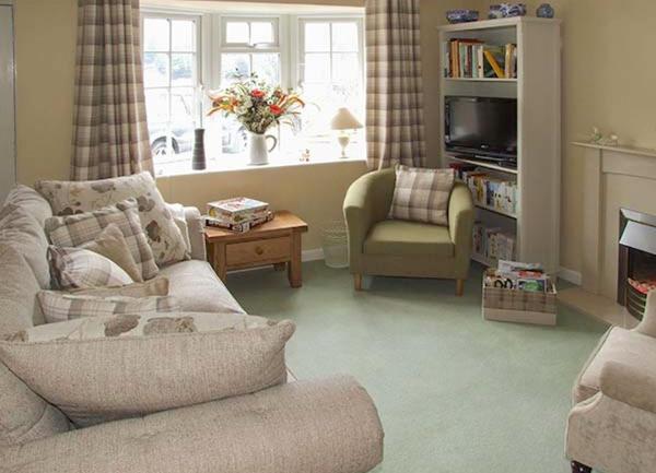 A lounge with a sofa, two chairs, bookshelves and an open fireplace.