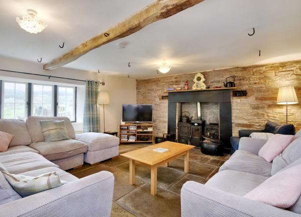 An oak-beamed lounge with a flagstone floor with wrap-around sofas seating 8.