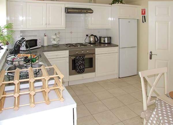 A kitchen with fitted units and wall cupboards with an integrated electric cooker, full height fridge-freezer and a microwave.