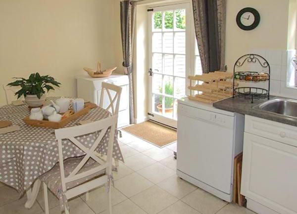 A kitchen corner with a table laid for breakfast and a dishwasher next to a kitchen sink.