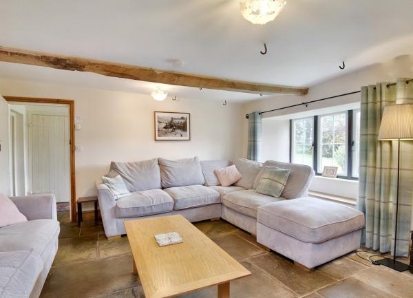 A flag-stone floor lounge with wrap-around sofas and a long wooden coffee table.