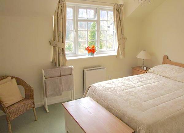 A double bedroom with a bed, bedside lights, towel rail and a bedside chair.