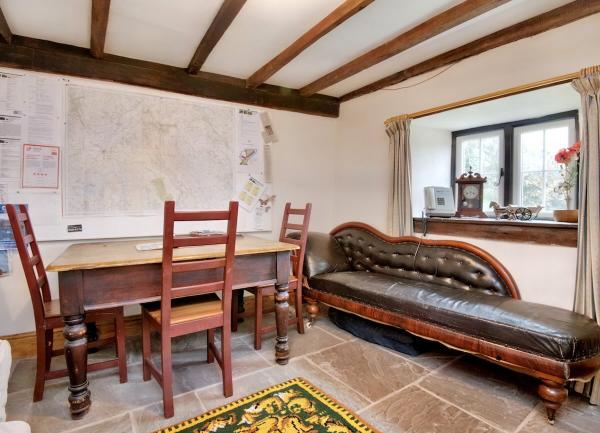 A snug with a wood table seating 3, leather chaise lounge and a Wye Valley map on the wall.