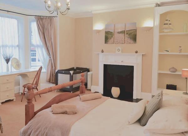 A doiuble bedroom with bed, fireplace, travel cot and dressing table