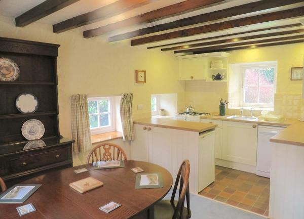 Dining area with a table for six and a dresser in front of a fitted kitchen.
