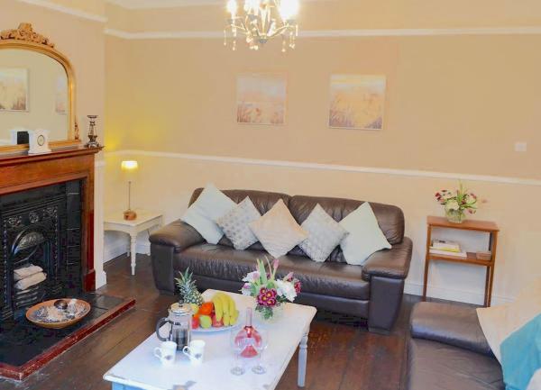 A living room with a leather sofa, coffee table and fireplace.