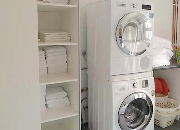A utility room with a tumble dryer stacked on a washing machine.