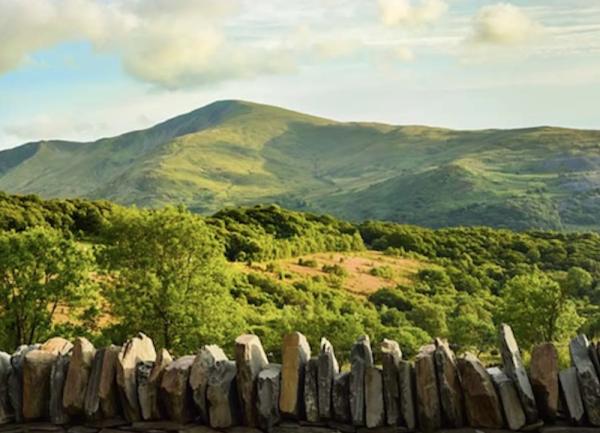 Beyond a low stone wall lie mountain views.